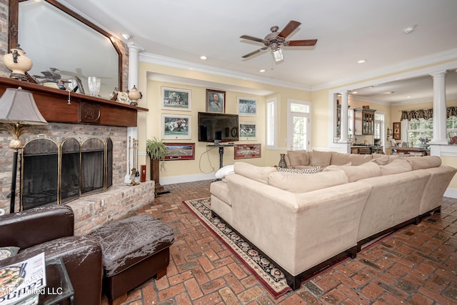 living room featuring brick floor, ornamental molding, ceiling fan, baseboards, and ornate columns
