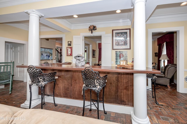 bar with bar, crown molding, recessed lighting, decorative columns, and brick floor