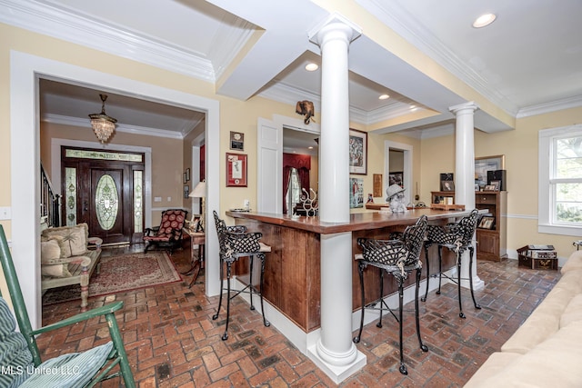 bar with ornate columns, ornamental molding, brick floor, and baseboards