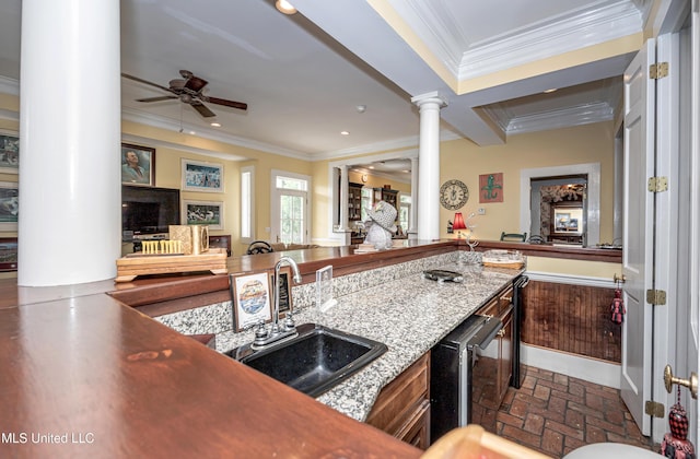 kitchen with crown molding, a sink, brick floor, and ornate columns