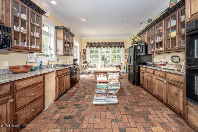 kitchen with glass insert cabinets, brick floor, black appliances, a sink, and crown molding