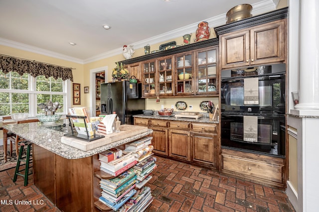 kitchen with black appliances, brick floor, ornamental molding, and light stone counters
