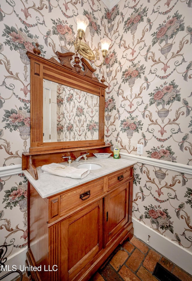 bathroom with baseboards, wallpapered walls, vanity, and brick floor