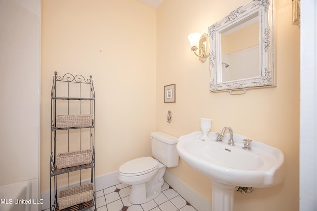 bathroom featuring toilet, a sink, tile patterned floors, and baseboards