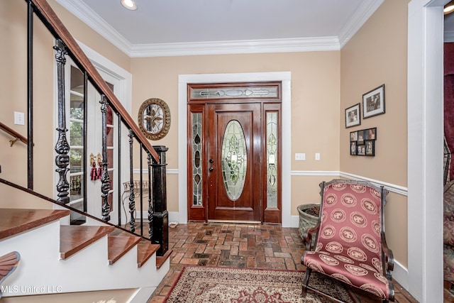 foyer entrance with stairway, ornamental molding, and brick floor