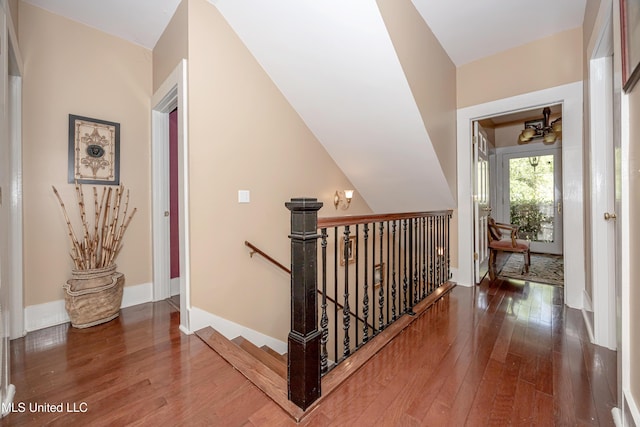 hallway with an upstairs landing, hardwood / wood-style floors, and baseboards