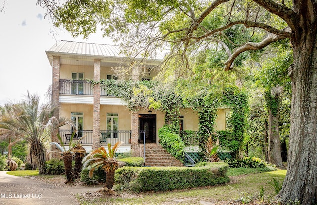 view of front of house with stucco siding, stairs, a balcony, and a porch