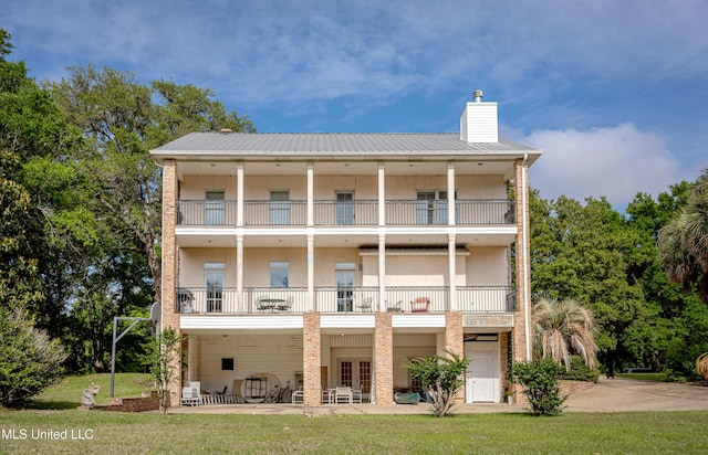rear view of house featuring a lawn, a balcony, a patio, and stucco siding