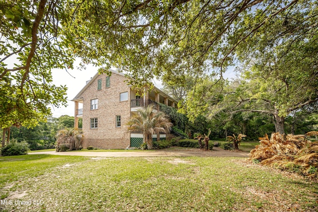 view of home's exterior featuring a lawn, brick siding, and a balcony