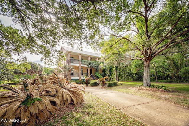 coastal home with stucco siding, concrete driveway, and a balcony