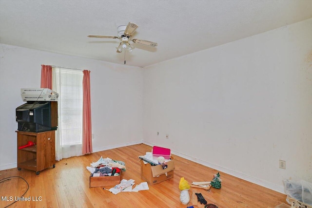 miscellaneous room featuring ceiling fan, wood-type flooring, and a textured ceiling