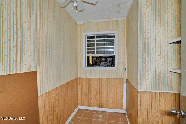 details with tile patterned floors, ceiling fan, wood walls, and a textured ceiling