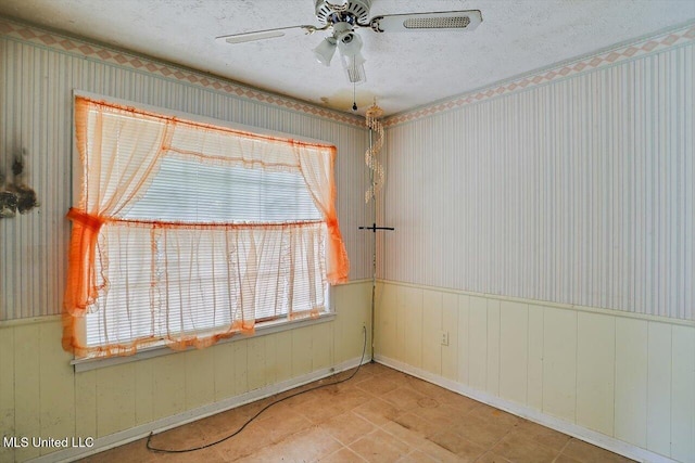 empty room with ceiling fan and a textured ceiling