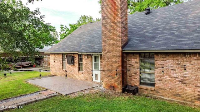 118 Dogwood Trl, Brandon, MS 39047 - back of property with a chimney, a patio, brick siding, a lawn, and a shingled roof