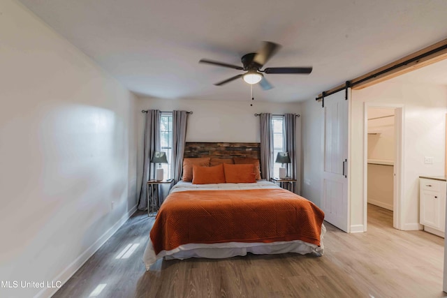 118 Dogwood Trl, Brandon, MS 39047 - bedroom featuring multiple windows, light wood finished floors, a barn door, and baseboards