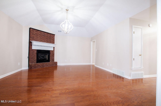 unfurnished living room with an inviting chandelier, lofted ceiling, wood-type flooring, and a fireplace