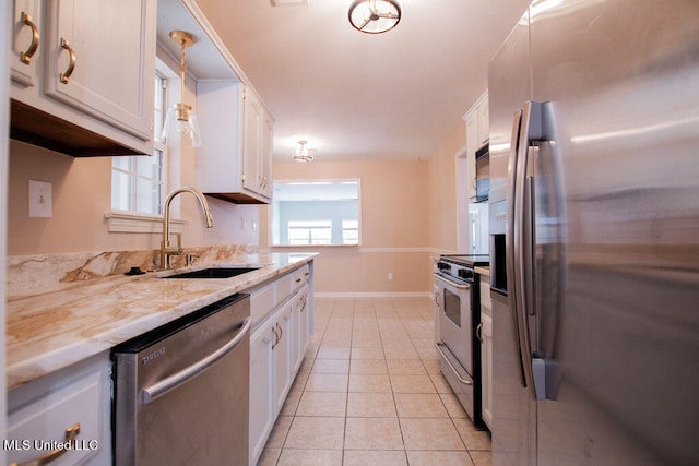 kitchen with stainless steel appliances, sink, light tile patterned floors, white cabinets, and pendant lighting