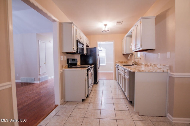 kitchen featuring range with electric stovetop, white cabinetry, stainless steel refrigerator, sink, and light hardwood / wood-style flooring