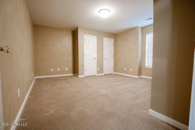 unfurnished bedroom with light carpet and two closets