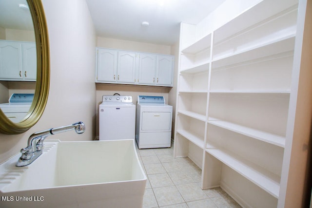 laundry room with washing machine and clothes dryer, cabinets, light tile patterned floors, and sink