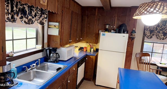 kitchen featuring wooden walls, white appliances, a sink, beamed ceiling, and dark countertops