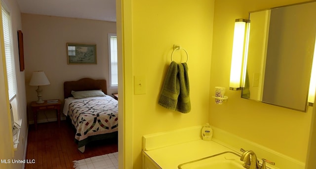 bedroom featuring wood finished floors, multiple windows, and a sink