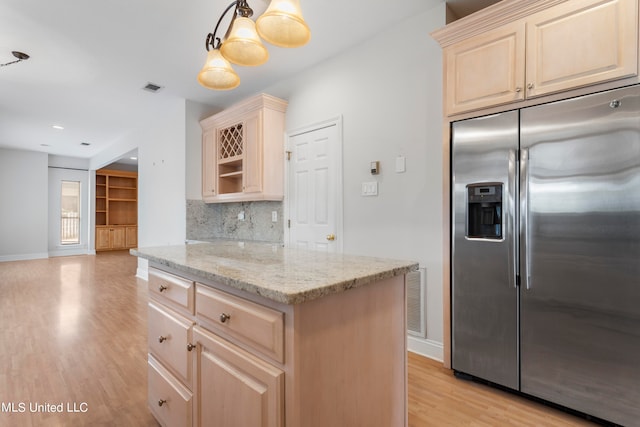 kitchen featuring light hardwood / wood-style flooring, hanging light fixtures, stainless steel refrigerator with ice dispenser, light stone counters, and tasteful backsplash