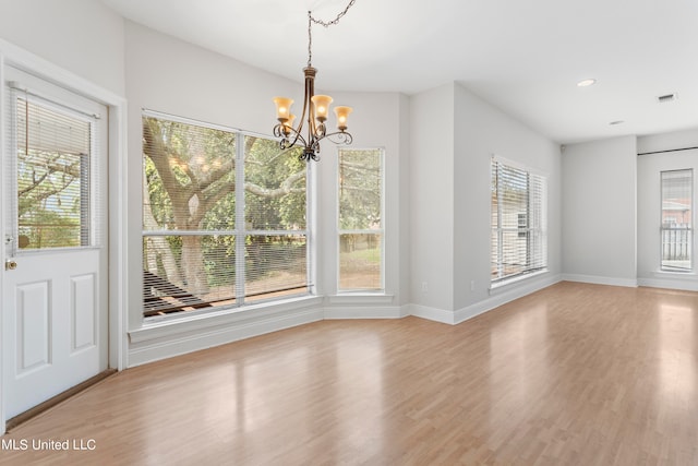 unfurnished dining area with light hardwood / wood-style flooring, a chandelier, and a wealth of natural light