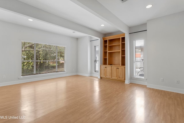 unfurnished living room with beamed ceiling and light hardwood / wood-style flooring