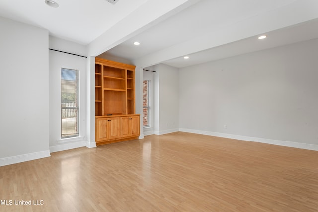 unfurnished living room with beam ceiling and light hardwood / wood-style flooring