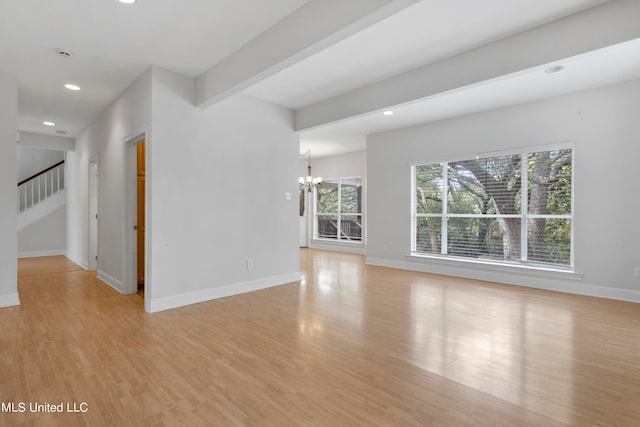 unfurnished living room featuring beam ceiling, a chandelier, and light wood-type flooring