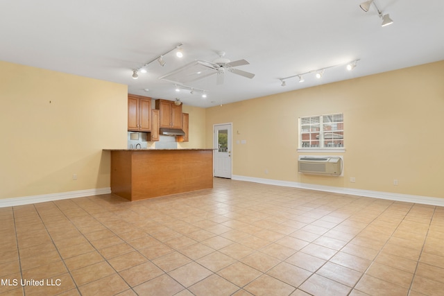 kitchen with light tile patterned flooring, track lighting, kitchen peninsula, and a wall unit AC