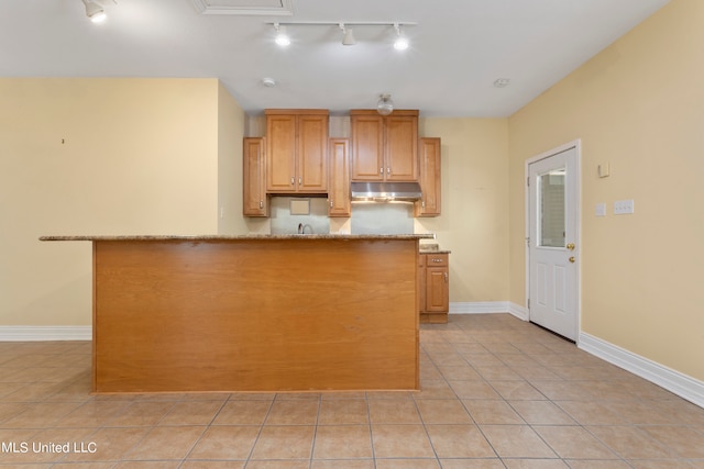 kitchen featuring kitchen peninsula, rail lighting, light tile patterned flooring, sink, and light stone counters