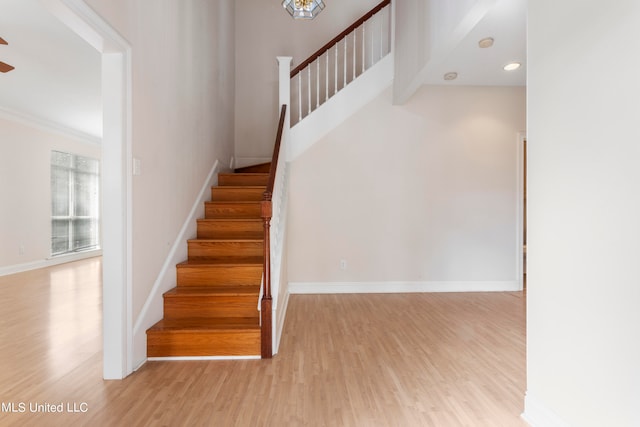 stairs with ornamental molding and hardwood / wood-style flooring