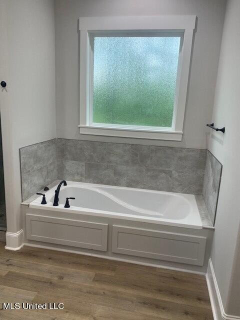 bathroom with hardwood / wood-style flooring and a washtub