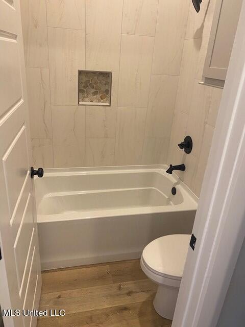 bathroom featuring toilet, tiled shower / bath, and hardwood / wood-style flooring