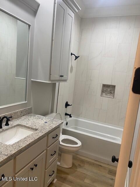 full bathroom with vanity, tiled shower / bath combo, toilet, and wood-type flooring