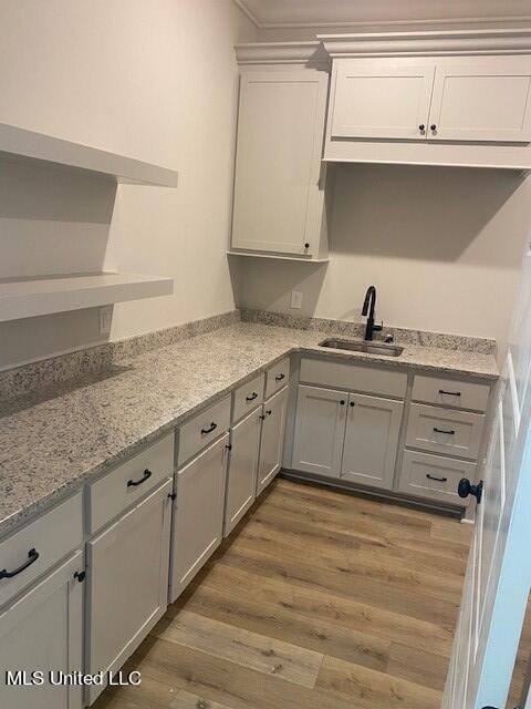 kitchen with sink, light stone countertops, gray cabinetry, and light wood-type flooring