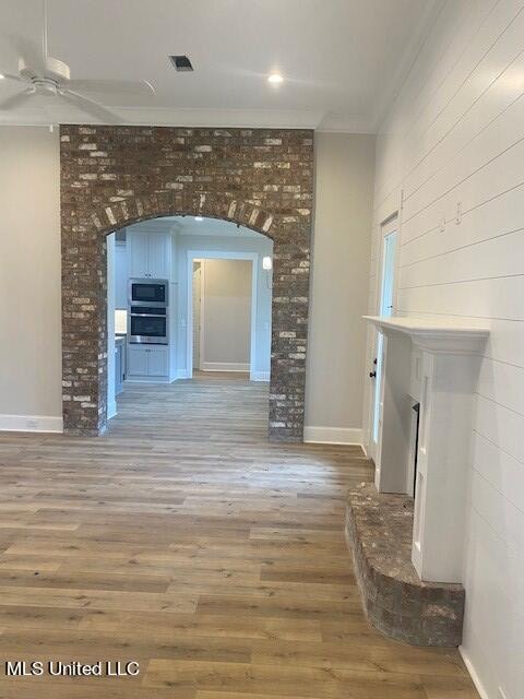 unfurnished living room with hardwood / wood-style floors, crown molding, and ceiling fan