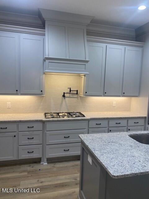 kitchen featuring gray cabinetry, light stone countertops, dark hardwood / wood-style floors, and stainless steel gas stovetop