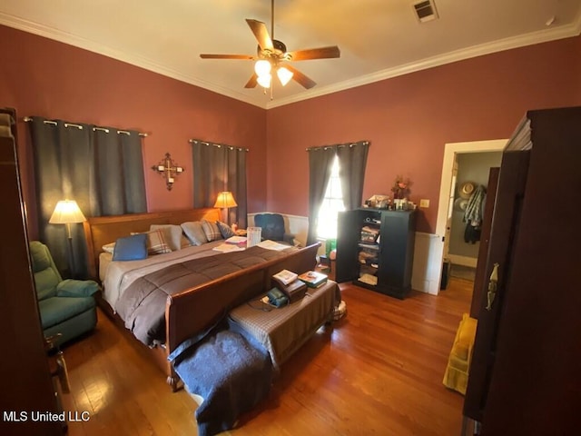 bedroom featuring a ceiling fan, visible vents, wood finished floors, and ornamental molding