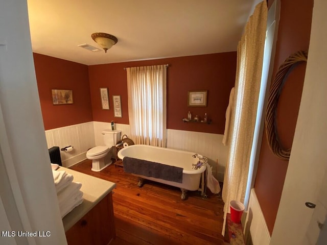 bedroom featuring wainscoting, wood finished floors, and visible vents