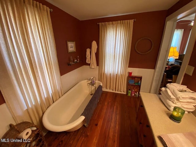 full bath with a wainscoted wall, wood finished floors, and a tub