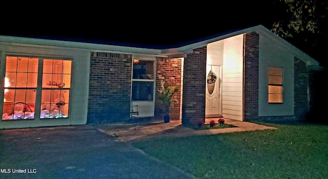 exterior space with brick siding and a front yard