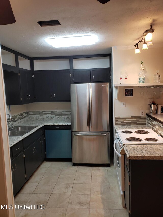 kitchen featuring white electric range, dishwashing machine, dark cabinetry, a sink, and freestanding refrigerator