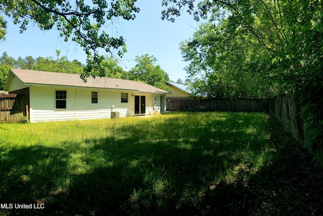 rear view of house with a lawn and a fenced backyard