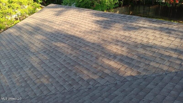 details featuring a shingled roof and fence