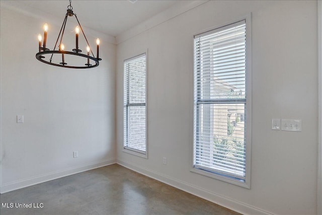 spare room with an inviting chandelier, crown molding, and concrete floors