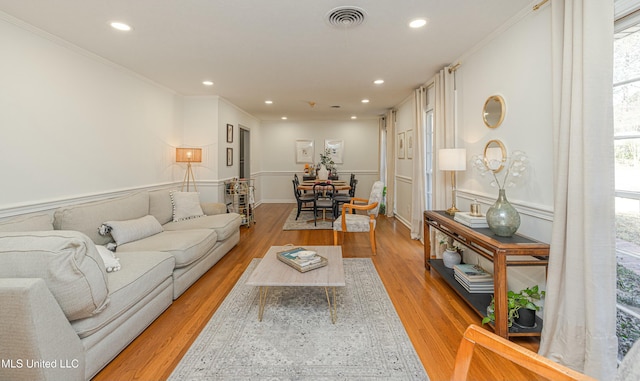 living area featuring light wood-style flooring, visible vents, ornamental molding, and recessed lighting