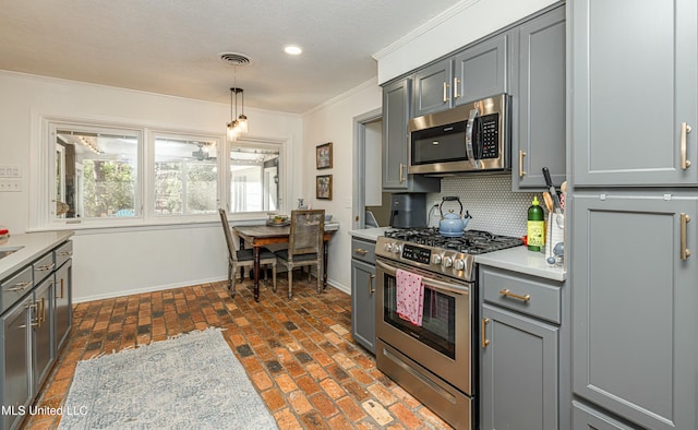 kitchen with visible vents, brick floor, stainless steel appliances, crown molding, and gray cabinetry